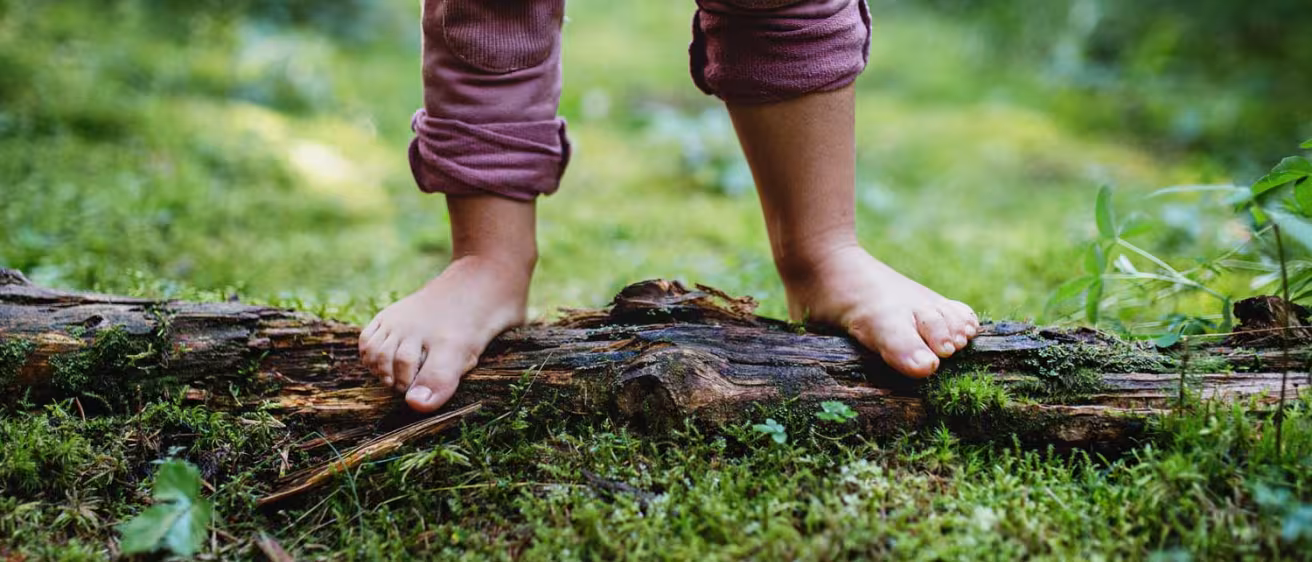 Bare feet of small child standing barefoot outdoors in nature