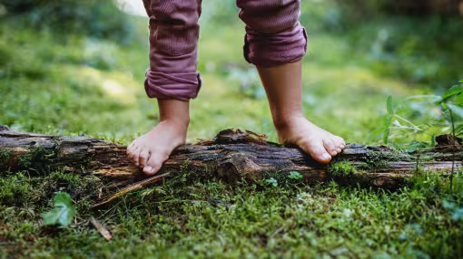 Bare feet of small child standing barefoot outdoors in nature