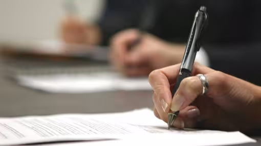 three hands in a row holding pen writing on paper