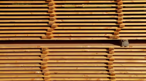 Stacks of evenly spaced, horizontal wooden planks drying in neat, symmetrical rows at a lumber yard.