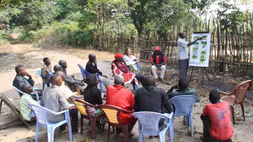 An outdoor community workshop taking place in a rural area of the Democratic Republic of the Congo.