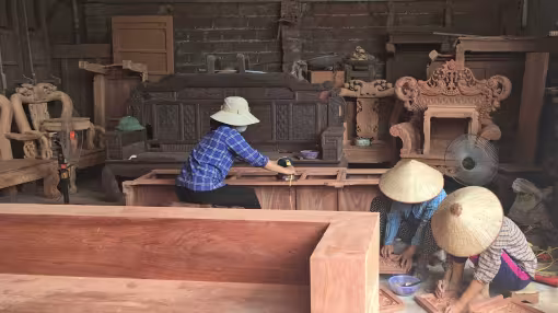 Three female artisans carving wood in a carpentry workshop, Viet Nam.