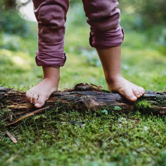 Bare feet of small child standing barefoot outdoors in nature