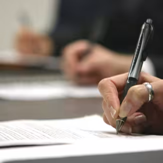 three hands in a row holding pen writing on paper