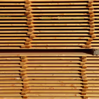 Stacks of evenly spaced, horizontal wooden planks drying in neat, symmetrical rows at a lumber yard.