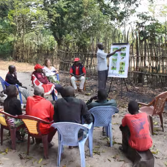 An outdoor community workshop taking place in a rural area of the Democratic Republic of the Congo.