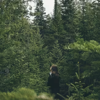 girl looking upwards in the forest